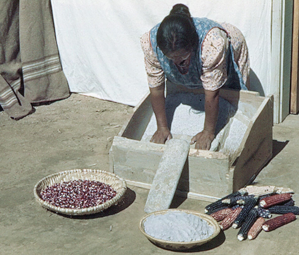 Navaho women grinding corn with a metate and mano.