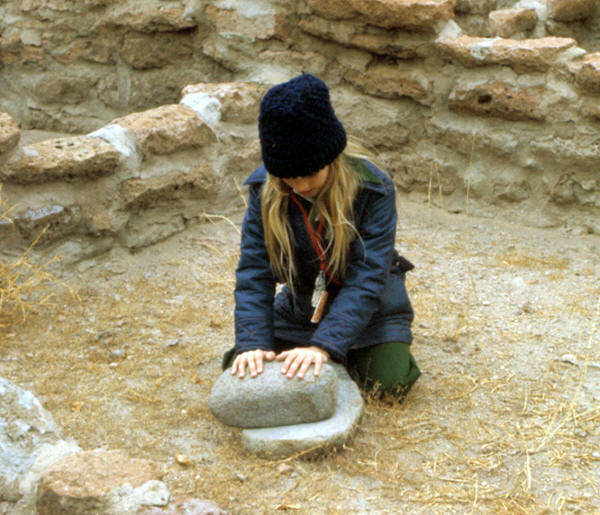 Girl demonstrating use of mano and metate.