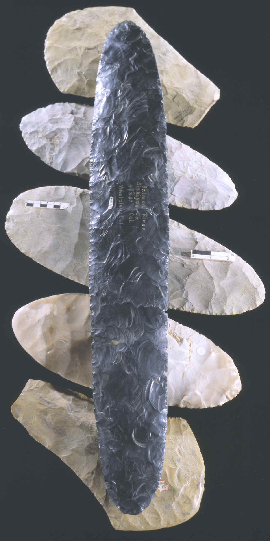 Large obsidian biface laying on 5 large spades.