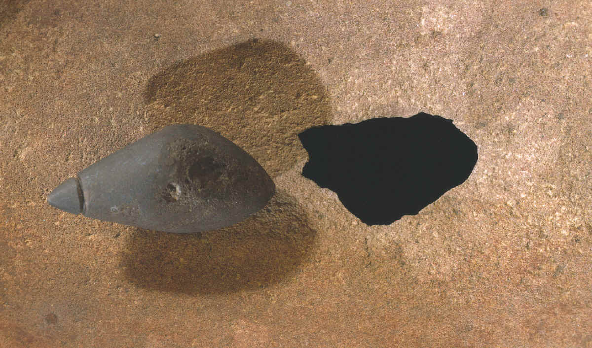 Hole worn through grinding stone with plummet.