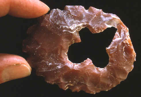 Mayan ring eccentric with quadrilateral hole in center.