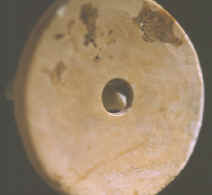 Shell bead with micro-drill sticking out from behind.